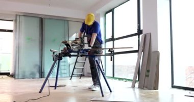 İşçi testereyle parke yapmak için tahta keser. İnşaatçı zemin kaplama malzemesi hazırlar