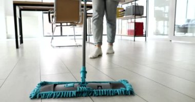 Temizlikçi kadın ofiste mikrofiber bezle yerleri paspaslıyor. 4K film yavaş çekimde. Ev temizliği hizmetleri kavramı