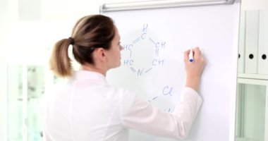Bilim adamı kimyager laboratuvarda karatahtaya kimyasal formül yazdığını keşfetti. Araştırmacı, hastaları tedavi etmek için aşı ya da ilaç keşfetti
