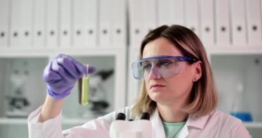 Bilim adamı deney tüpünde şeffaf sıvının laboratuvar testlerini yapıyor. Kimyasal veri edinme kavramı