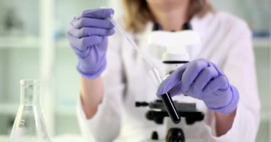 Bilim adamı laboratuardaki ham yağ test tüpüne temiz sıvı damlatıyor. Petrol ürünlerinin, yakıtların ve kayganlaştırıcıların incelenmesi