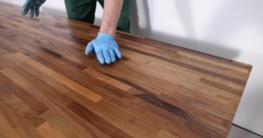 Ahşap yüzeyi koruyucu vernikle kaplayan marangoz ellerinin yakın çekimi. Marangozluk mobilyaları cilalıyor.