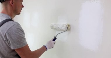 Ressam el boyama duvarını silindirle kapatıyoruz. Usta bir inşaatçının yüksek kaliteli duvar resmi.