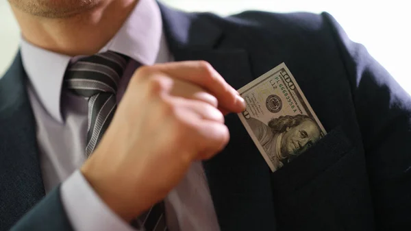 ビジネスマンは上着のポケットから１００ドル札を持ち出した ビジネスコンセプトの贈賄 — ストック写真