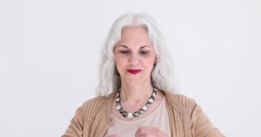 Pozitif gri saçlı kadın ellerinin kameraya baktığı kalbi şekillendirir. Tatmin olmuş olgun bir bayan aşkı ve sevgiyi yavaş çekimde gösterir.