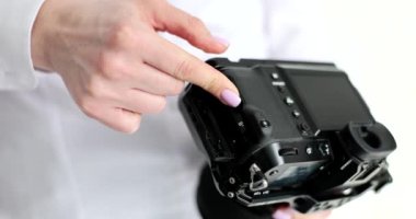 Kadın, profesyonel kamera kapanış kapağına hafıza kartı koyuyor. Fotoğrafçı, stüdyoda yavaş çekimde fotoğraf çekmeye hazır modern bir cihaz kuruyor.