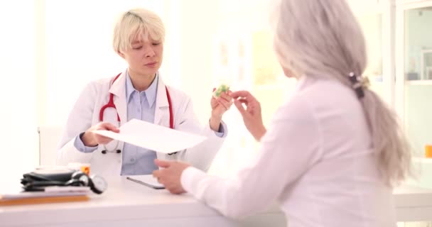Blond Familjeläkare Ger Behandlingsplan Och Plastflaska Med Piller Till Mogen — Stockvideo
