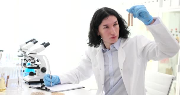 호기심많은 사람은 시험관에 밀알을 바라본다 과학자들은 실험실의 동작으로 현미경으로 곡물을 — 비디오