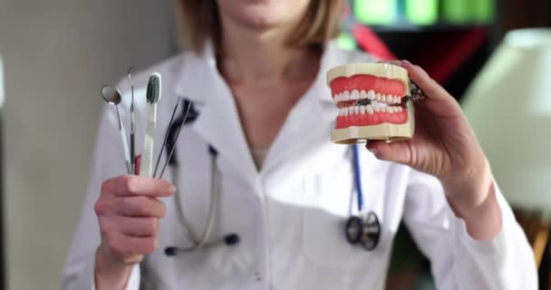 Kvinna Medicinsk Uniform Visar Modell Käkar Och Dentala Verktyg Händerna — Stockvideo
