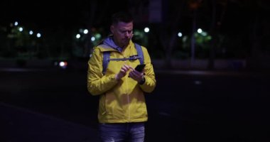 Erkek turist tren istasyonunu bulmak için akıllı telefondan navigasyon kullanıyor. Bilinmeyen bir şehirde çaresiz bir adam kayboldu. Gece ağır çekimde sokakta durdu.
