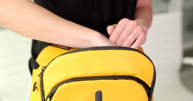Kadın kamerada gösterilen sarı sırt çantasından yığınla para alıyor. Kadın kişi yavaş çekimde satışlardan kazanılan parayı gösteriyor