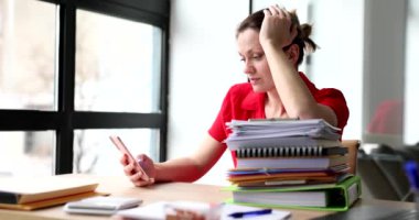 Yorgun kadın sosyal medyayı kontrol ediyor evrak işlerine ara veriyor. Yoğunlaştırılmış sekreter, iş yerinde ağır çekimde akıllı telefon kullanır.