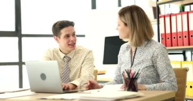 Meraklı meslektaşlar verileri karşılaştıran dizüstü bilgisayarlara ve araştırma belgelerine bakarlar. Heyecanlı erkek ve kadın takım projesinde birlikte oturuyorlar.