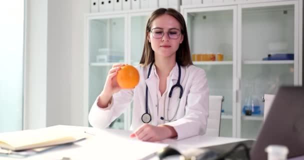 Ystävällinen Naispuolinen Lääkäri Lasit Pitää Tuoretta Oranssia Kädessä Katsoen Kameraan — kuvapankkivideo
