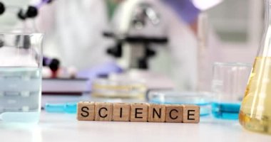 Kelime Bilimi, profesyonel laboratuvar bardaklarının yanında kimyasal sıvıyla yapılmış ahşap küplerden yapılmıştır. Bilimsel araştırma ve inceleme kavramı