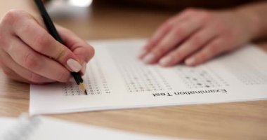Bayan öğrenci üniversitede sınav kağıdında doğru cevabı vurguluyor. Kadın, geçmiş akademik yıldaki bilgileri yavaş çekimde kontrol ediyor