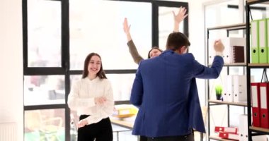 Resmi kıyafetler içindeki mutlu meslektaşlar modern ofiste birlikte dans etmekten hoşlanırlar. Neşeli takım, ortak girişim projesinin başarısını yavaş çekimde kutluyor