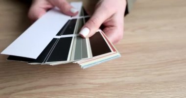 Kadının elleri ahşap masanın üstündeki renk paletinden yelpaze yapıyor. Tasarımcı, iç tasarım yavaş çekim için duvar kağıtlarının renk çeşitlerini sunar