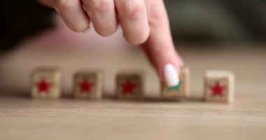 Yeşil yıldızlı tahta küpü alıp masaya koyan bir kadın eli. Liderlik kavramı ve uymama yavaş çekim