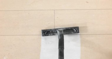 İşçi, yenileme sürecinde oturma odasındaki lamine zeminde endüstriyel temizlik yapıyor. Elektrikli süpürge, zemindeki küçük talaşları ağır çekimde temizliyor.