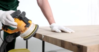 Koruyucu eldivenli ustabaşı ofis için ahşap masa kenarlarını cilalamak için modern öğütücü makine kullanıyor. İnsan ahşabı ağır çekimde işler.