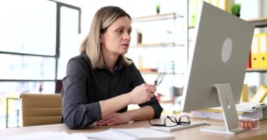 Şüpheli kadın büyüteçten bilgisayar ekranına bakıyor. Kadın çalışan yavaş çekimde küçük yazı tiplerini okumaya çalışıyor