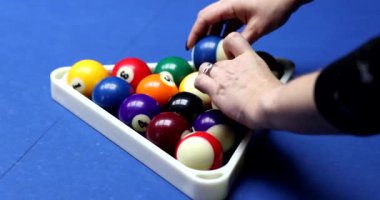 Kadın, mavi bilardo masasında parmakları olan çok renkli toplardan piramit yapıyor. Kadın oyuncu bilardo oynamak için topları yavaş çekimde hazırlar.