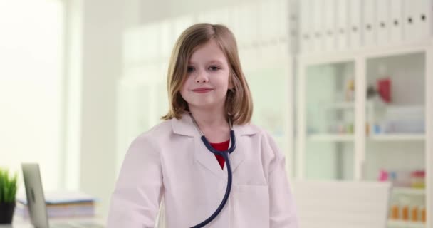 健康診断の準備ができている聴診器を医療制服のかわいい女の子が示しています 正の子供は 将来の職業の遅い動きを夢見て笑顔 — ストック動画