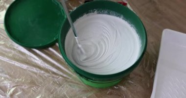 Foreman, filmin üzerinde duran duvarları işlemek için yeşil kovada alçıyı hazırlamak için mikser kullanır. Uzman, yavaş çekimde tadilat yapıyor.