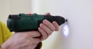 Foreman sondaj makinesiyle duvarda küçük delikler açıyor. Uzman, ağır çekimde tadilat yapan profesyonel ekipmanlarla çalışıyor.