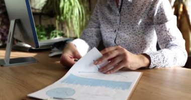Sekreter, ahşap masada oturan panodaki istatistiklerle soruşturma kağıtlarını çeviriyor. Kadın yazılı belgelerin bilgilerini yavaş çekimde kontrol ediyor