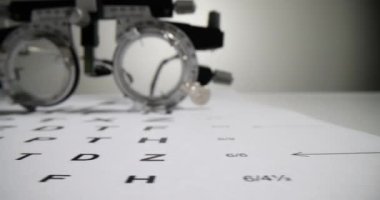 Ofisteki Snellen dosyalarının olduğu beyaz kağıdın üzerinde oftalmoloji gözlükleri var. Görme kontrolü için profesyonel tıbbi ekipman.