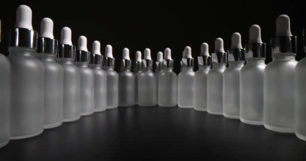 装有面部血清的酒瓶和喷雾器在深色桌面上倒入一排弯曲的倒影 黑色背景的专业护肤化妆品 — 图库视频影像