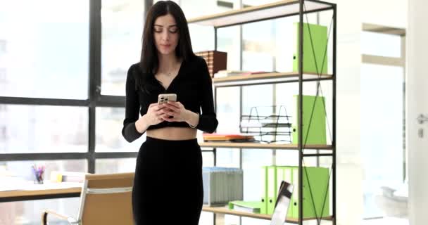 专心致志的女人通过智能手机回复朋友的留言会分散工作的注意力 布鲁内特的秘书在办公室里用小玩意慢动作 — 图库视频影像