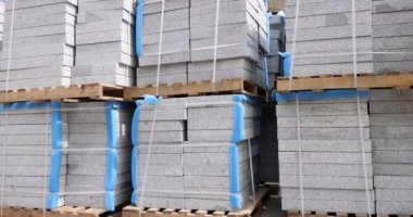 Yığılmış taş kaldırım levhaları, ahşap tepsilerde, 4 km 'lik ağır çekimde yatıyor. İnşaat malzemeleri konsepti satışı