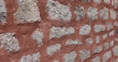 Şehir sokağındaki kırmızı çimento ve taştan duvar. 4K 'lık yakın çekim. Ağır çekim. Binaların tasarımı ve mimarisi