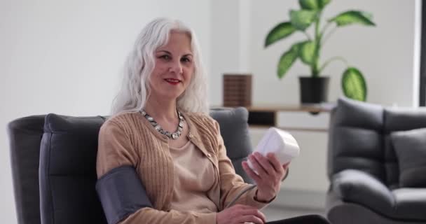 笑顔の高齢女性は血圧と親指を測定します 年金受給者における血圧測定のための推奨 — ストック動画