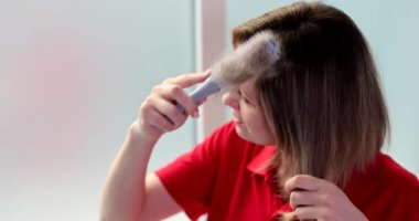 Mutsuz, şok olmuş, elinde tarak olan kadın saçlarına bakıyor. Saç kaybı ve sağlık sorunları