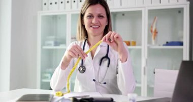 Doktor diyetisyen klinikte mezura tutuyor. Sıhhiye sağlıklı yiyecek ve diyet öneriyor