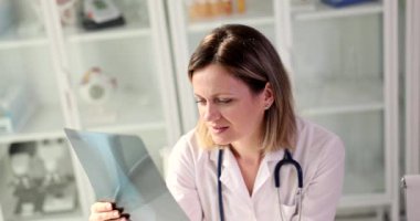 Odaklanmış kadın doktor travmatolog röntgenleri analiz ediyor. Doktor kırığı inceliyor.
