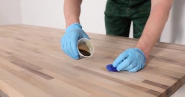 Usta marangoz ahşap masayı özel yağla kaplıyor. Ahşap ürünlerin korunması