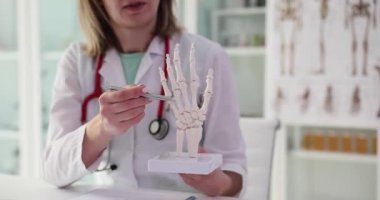 Doktor travmatolog, el iskeletinin anatomisini tutuyor. Ağrı ve bilekteki kemiklerin tedavisi sorunu