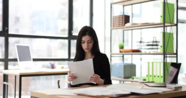 Yorgun bayan yönetici belgeleri okur, atar ve ofisten çıkar. Çalışma gününün sonu