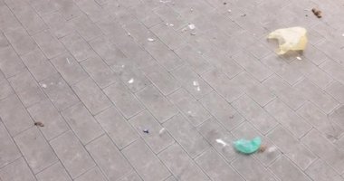 Rüzgar kaldırım boyunca plastik poşet ve sigara taşır. Sokakta çöp.