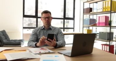 Erkek müdür çok kızgın ve cep telefonuna bakıyor. İş yerindeki sorunlar onu şok ediyor. Sinirli adam akıllı telefondan gelen mesaj veya hatadan memnun değil