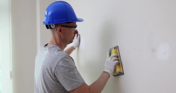 男性ビルダーは部屋にパテで壁をきれいにします 表面の高品質なパテマスターは 電動工具で古いパテを削除します — ストック動画