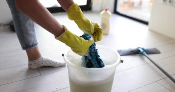 戴手套的妇女把微纤维布挤进装满水和泡沫的桶里 清洁服务办公室或家居清洁 — 图库视频影像