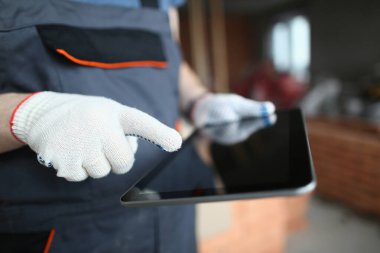 Eldiven ustası inşaat ve onarım için tablet kullanıyor. Daire yenileme uygulamaları ve yardımları