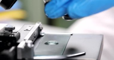 Mikroskop merceğinin lensleri bir damla sıvının üstünde, yakın plan. Kimyasal laboratuvar, su testi.