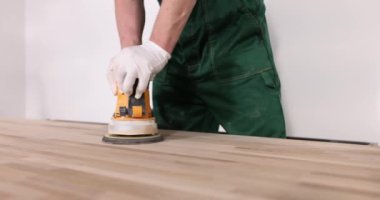 Bir marangoz, ahşap bir çarşafı öğütücüyle cilalar. Yakın plan. Ekipman ve marangoz işi, tezgah onarımı.